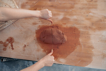 Female master working with raw clay in pottery room