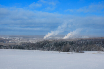 Fototapeta premium Canadian countryside winter landscape with industries belching smoke into the sky.