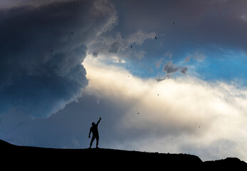 Silhouette of a person stands on the on the hill on  the sunset background.