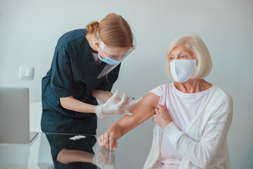 Nurse giving injection to senior woman in living room