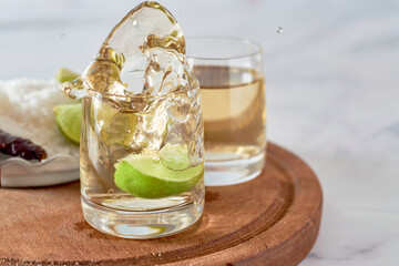 Lime slice falls into a glass with mexican tequila