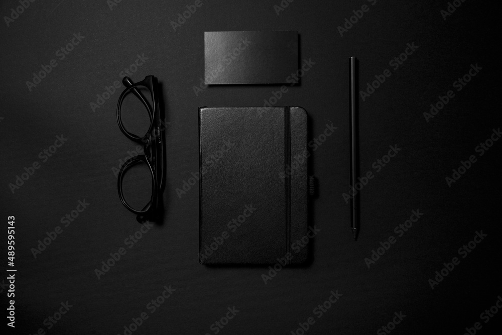 Wall mural Mock up business template. Black blank business card stationery on black desktop with office supplies