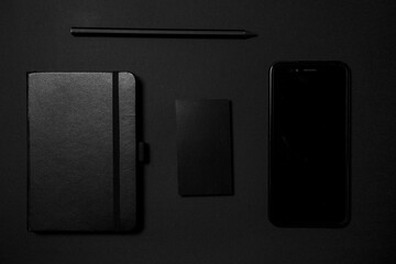 Mock up business template. Black blank business card stationery on black desktop with office supplies