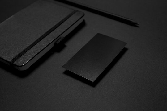 Mock up business template. Black blank business card stationery on black desktop with office supplies