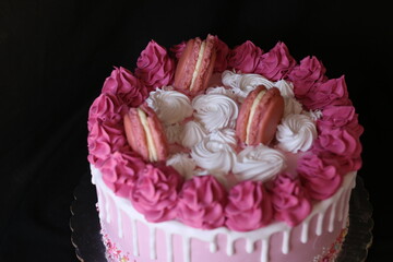Confectioner's hands hold a pink cake, black background