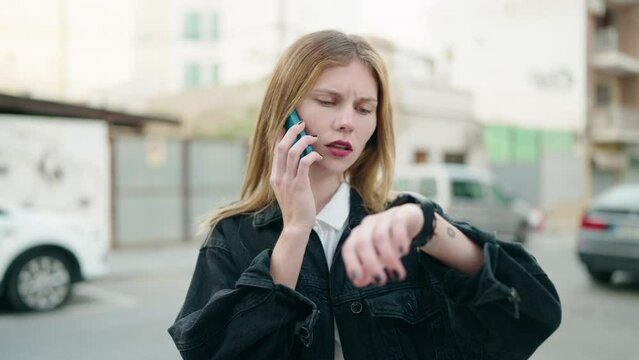 Young caucasian woman talking on the smartphone looking watch at street