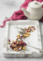 Rose buds mix tea in wooden box with tea vintage strainer infuser and teapot on white background with red cloth