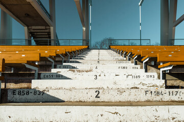 Numbered steps in the sports stadium between the wooden seats in Turku, Finland. Concrete stairs at the empty stadium without the spectators captured in the winter day.