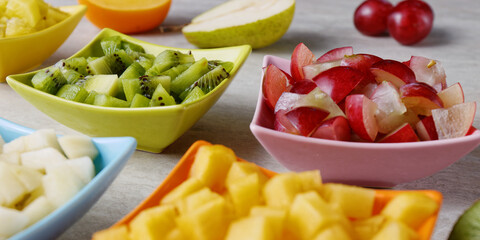 Colorful fruits snacks assortment in small bowls. Raw fresh chopped fruit on a table.
