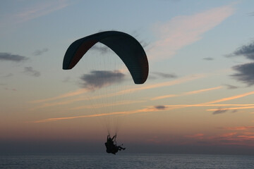 Paragliding silhouette, paraglider pilot fly in sky on beauty nature beach sky background, horizontal photo