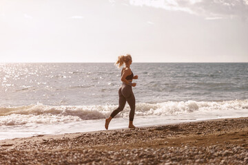 Athletic woman running on beach by sea