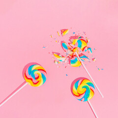 Multi-Colored Whole And Broken Lollipops on pastel pink background, top view. Sugar detox and junk food concept.