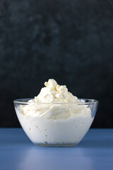 Cooking meringue. Whipped egg in the glass bowl, over gray texture background, blue table. Baking dessert concept. You just need to mix whisked egg whites and sugar. Perfect combination. Copy space.