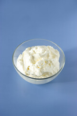 Easy recipe of meringue cookies top view. Vertical plane. Whipped egg whites cream to perfect peaks in glass bowl on blue table. Add some sugar and mix. Cooking at home.
