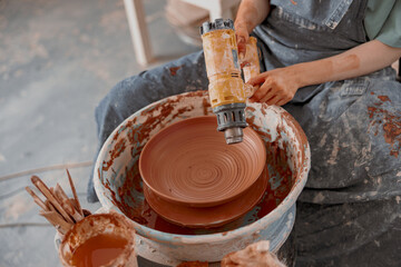 Young potter makes ceramic dish in art studio