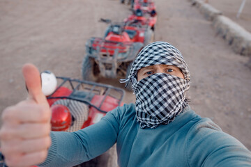 Man tourist make selfie photo on quad bike ATV safari in desert Sharm Hurghada, Egypt