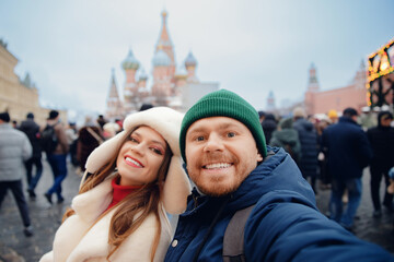 Happy friends man and woman making selfie photo and walking in city Christmas market. Winter...