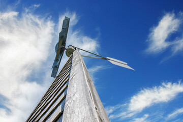Looking up at large metal weathervane of a wooden structure, blue sky and clouds, nobody - obrazy, fototapety, plakaty