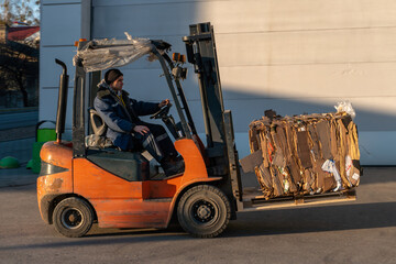 The forklift operator works on the territory of the store. Transportation of goods on a forklift truck. Waste paper loading, paper recycling plant. © Pokoman