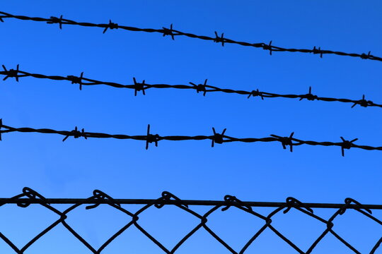 Barb wire against a clear blue sky. Chain link metal fence. Close up, or part of a metal fenece. Stockholm, Sweden, Europe.