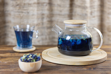 Dried flowers and a cup of pea, blue Anchan tea on a wooden table in a rustic style. Selective focus.