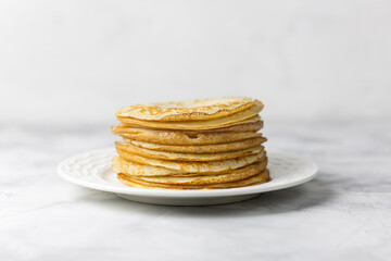 homemade pancakes, stacked on a white plate. National Russian and Ukrainian dish for Maslenitsa. Selective focus.