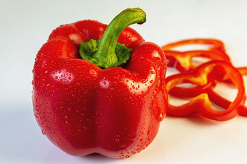 Bulgarian red pepper close-up on a light background. In the background, sliced pieces of red pepper