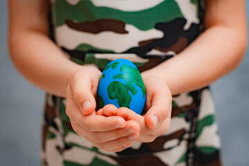 planet Earth in the shape of an egg in children's hands close-up. The concept of global problems of...
