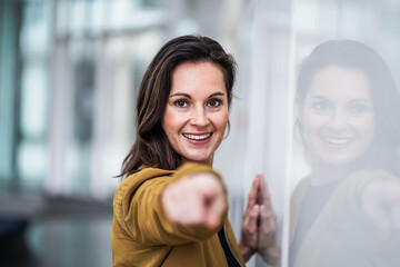 happy smiling casual business woman pointing finger at camera to address you directly for...