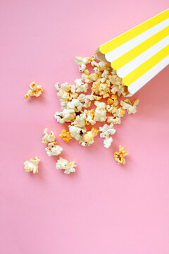 Spilled popcorn on pink background. Movie night concept. Copy space for text