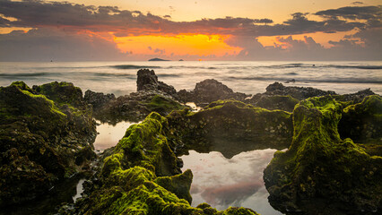sunset landscape on the beach rocks in foreground