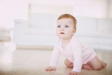 Exploring the floor- baby crawling. Shot of a little baby girl crawling on the floor indoors.
