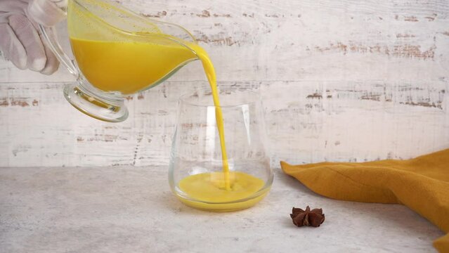 Golden moon milk with turmeric is poured into a glass. Healthy detox drink.