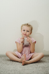 cute cheerful blonde girl drinks a milkshake with a straw