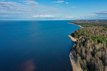 Fototapeta na wymiar Aerial view of the coastline of the Gulf of Finland. Sandy coast and forest belt. Treetops, blue sky.