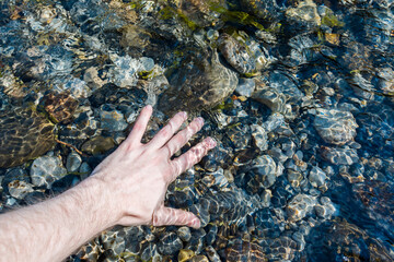 Close up man hand in fresh water stream clear refreshing drinking water in the forest. Clean water natural resource running spring