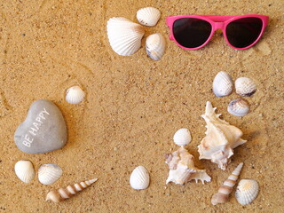 Glasses and various types of shells lie on the beach sand in the center there is a place for your notes - copyspace