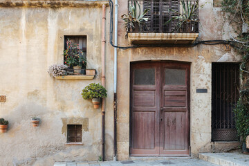 Fototapeta na wymiar An old wall, door, plants, and windows in Tarragona, Spain