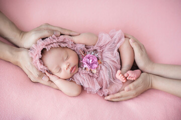 father and mother hand holding adorable cute Asian newborn baby sleeping on pink background