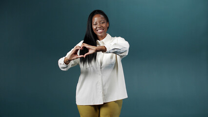 A handsome african woman is showing a heart from her hands 