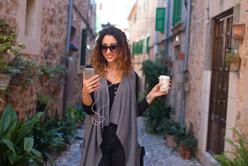 Young woman walking the cobblestone streets of an old tourist sea town