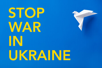 Stop war in Ukraine text in yellow on blue next to a white paper dove, peace