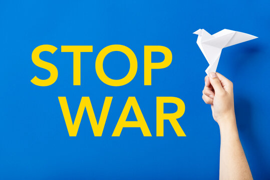 Stop war text in yellow on blue next to a white paper dove, symbol of peace