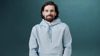 A bearded man takes off his mask, smiles and looks at the camera