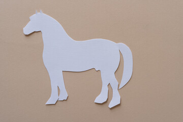 paper silhouette of a white horse on beige paper