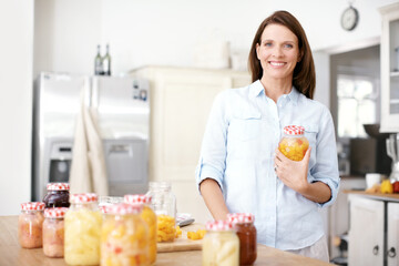 Happily working in the kitchen. Portrait of a mature woman standing with a jar in the kitchen.