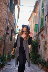 Fototapeta na wymiar Young woman walking the cobblestone streets of an old tourist sea town