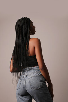 Back view of young afro American woman with long braids posing over white wall.