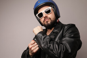 Cropped portrait of bearded biker in leather jacket and motorcycle helmet.