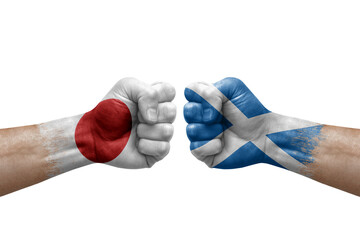 Two hands punch to each others on white background. Country flags painted fists, conflict crisis concept between japan and scotland